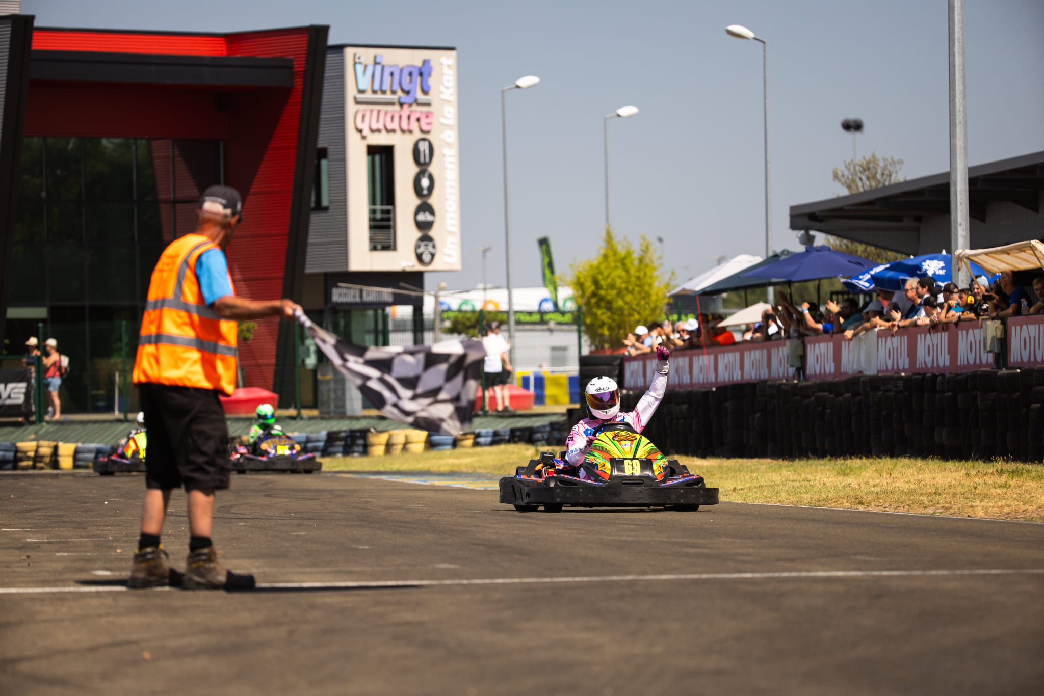 Marshal waving the checkered flag as a kart crosses the finish line
