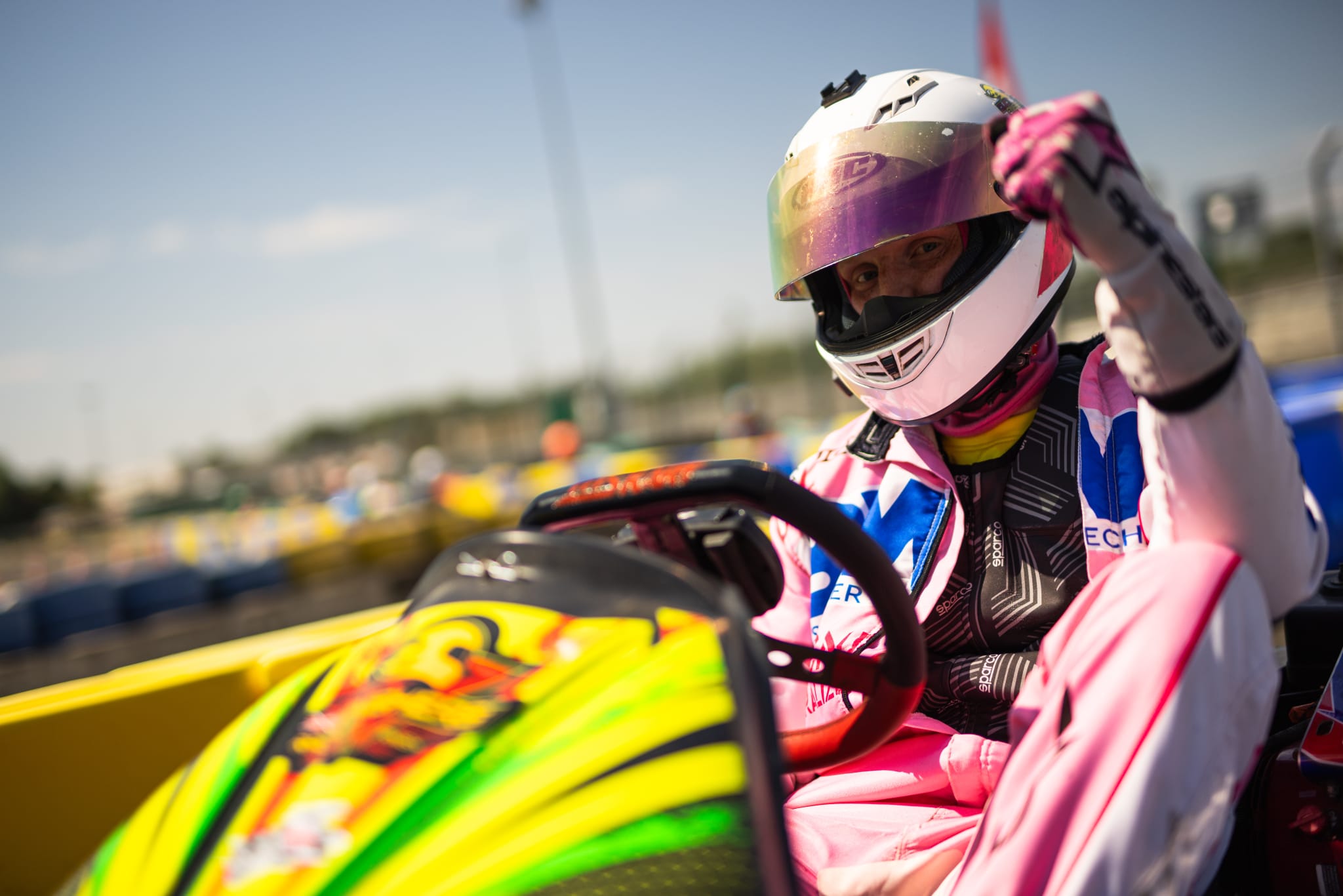 Close-up portrait of a driver in a white helmet with a gold mirrored visor