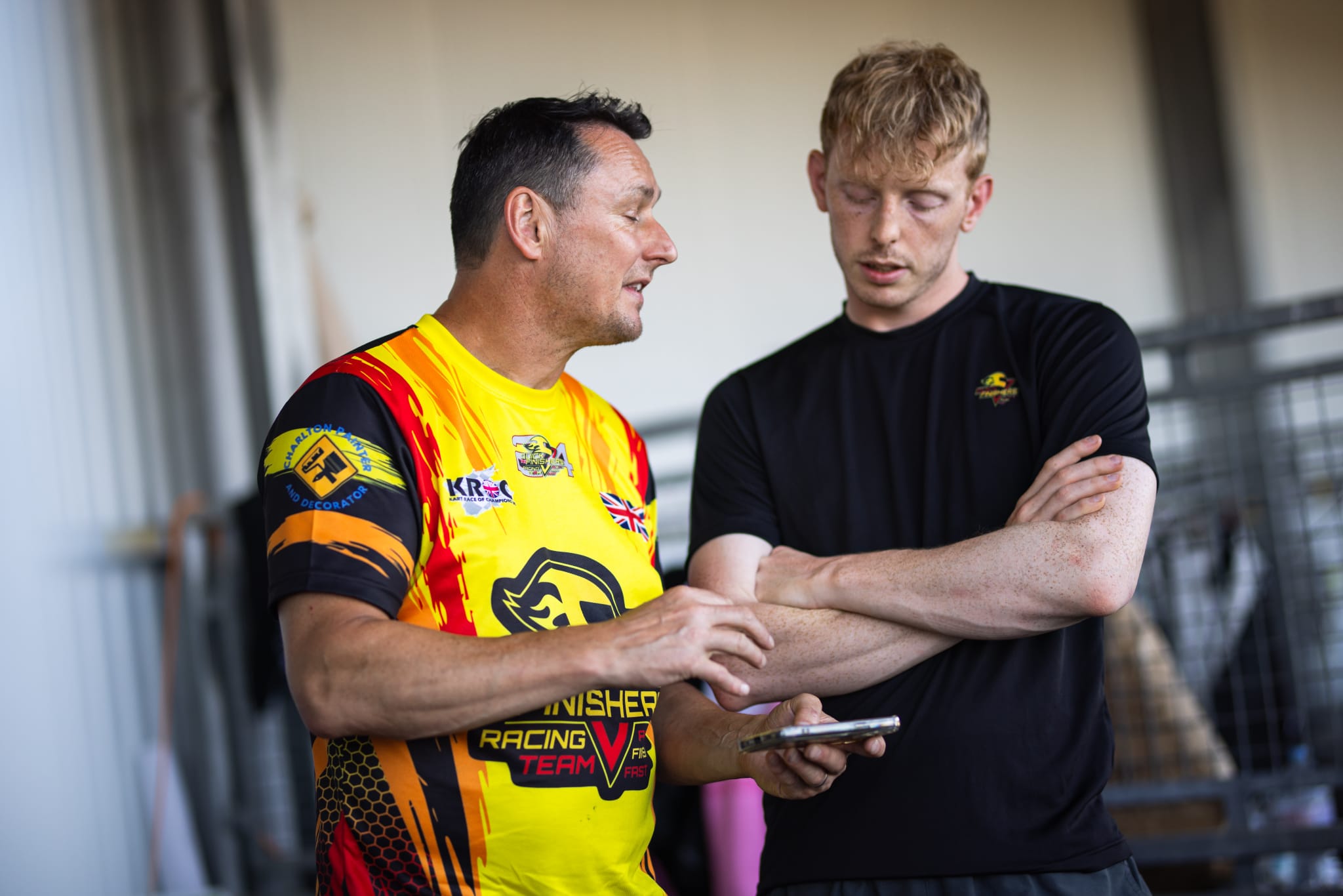 Two teammates talking and checking a phone before a race